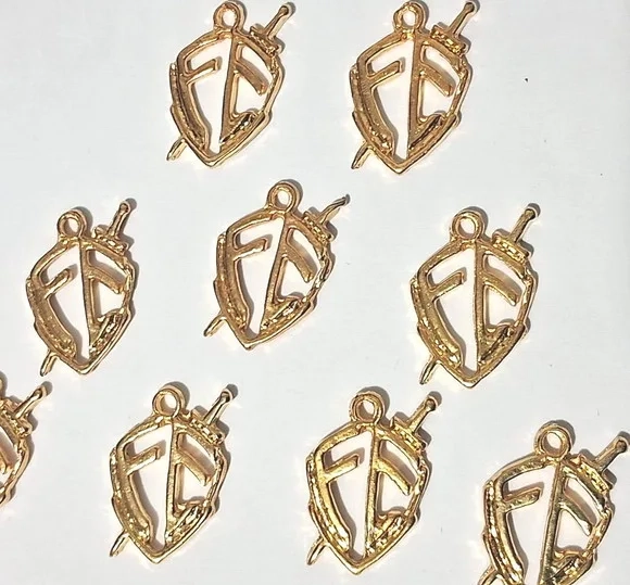 Pingente Escudo Fé de Metal Dourado e Prata Pacotes com 10 U